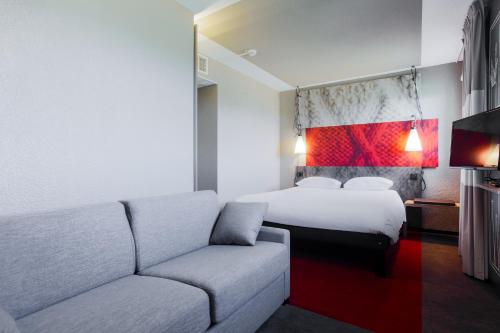 Habitación de hotel con cama y sofá en ibis Carcassonne Est la Cité, en Carcassonne