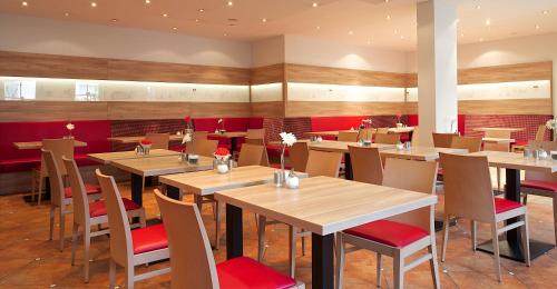 a restaurant with wooden tables and red chairs at Bed&Breakfast Erber in Ismaning
