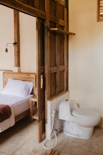 a bathroom with a toilet and a bed in a room at Kalyssa Beach Bungalows in Pemuteran