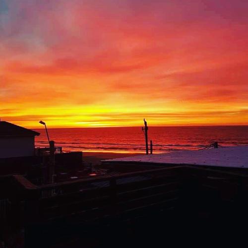 a sunset over the ocean with a person walking on the beach at El Bodegón Hostal Boutique in Punta Del Diablo