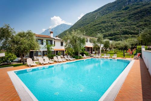 una piscina con sedie, una casa e le montagne di Residence Alesi a Malcesine