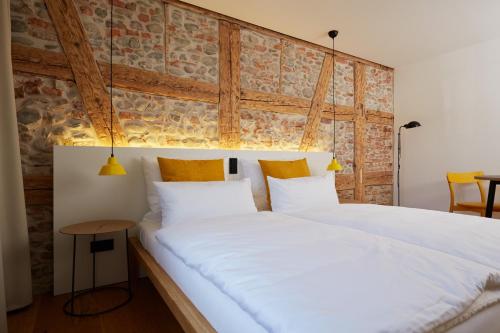 a bedroom with a large white bed with a brick wall at Sternen Bohlingen Aparthotel in Singen
