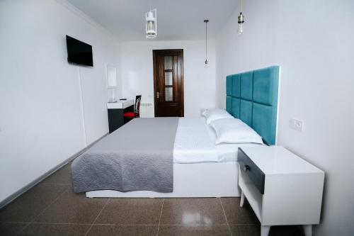 a bedroom with a large white bed with a blue headboard at Hotel Tamar Mepe in Kutaisi