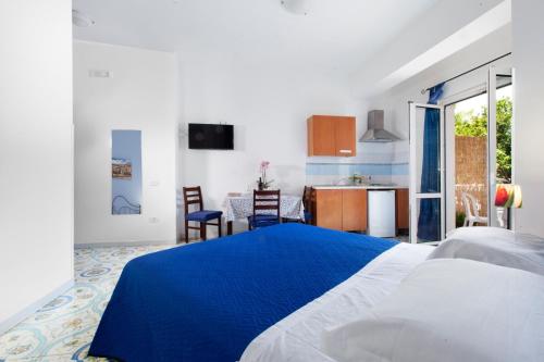 a bedroom with a blue and white bed and a kitchen at Sorrento Marida Rooms in Sorrento