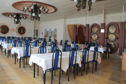 a dining room with white tables and blue chairs at Zheleznovodskaya Klinika Sanatorium in Zheleznovodsk