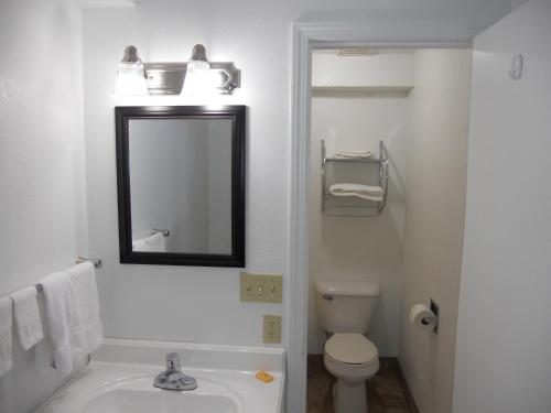 a bathroom with a sink and a toilet and a mirror at Knights Inn Harrisonville in Harrisonville