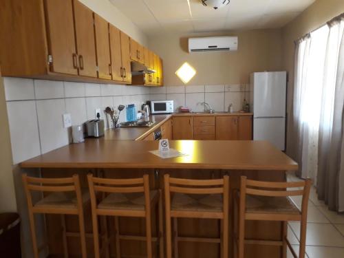 a kitchen with a wooden table and a refrigerator at Augrabies De Oude Stoor Guesthouse in Augrabies