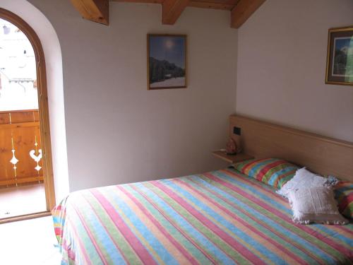 a bedroom with a bed with a colorful striped blanket at Casa Bamby in Cogolo