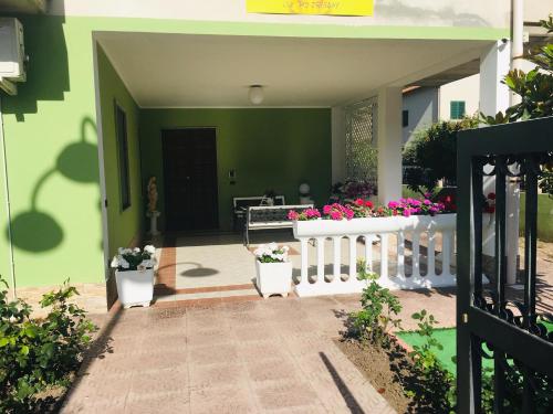 a house with a white fence and flowers at La Dea Hestia in Bosa