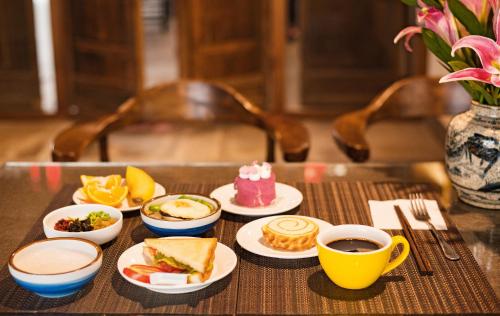 a table with plates of food and cups of coffee at Secret Courtyard Resort Hotel in Guilin