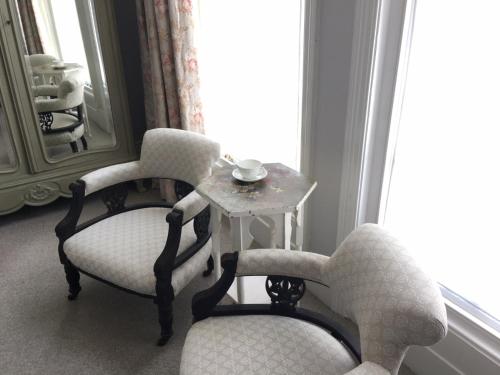 a room with two chairs and a table and a mirror at Anne’s House in Hastings
