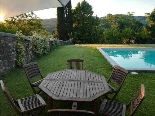 uma mesa de madeira e cadeiras ao lado de uma piscina em Villa storica di Majano em Bagno a Ripoli