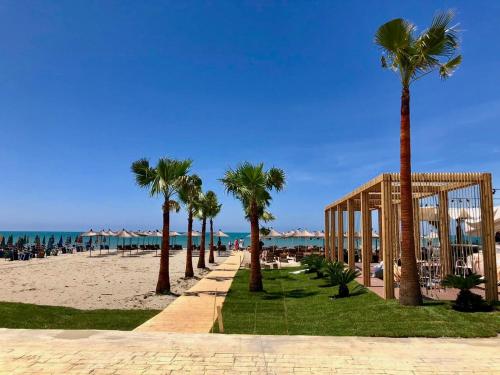 a row of palm trees on a beach with the ocean at Delight Apartments in Golem