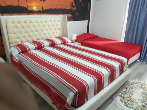 a bedroom with a bed with a red and white striped blanket at Hostal Africa Do Sul in Lisbon