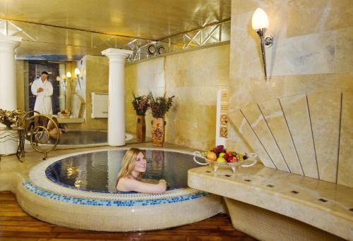 a woman laying in a bath tub in a bathroom at Imperial Hotel & Restaurant in Vilnius