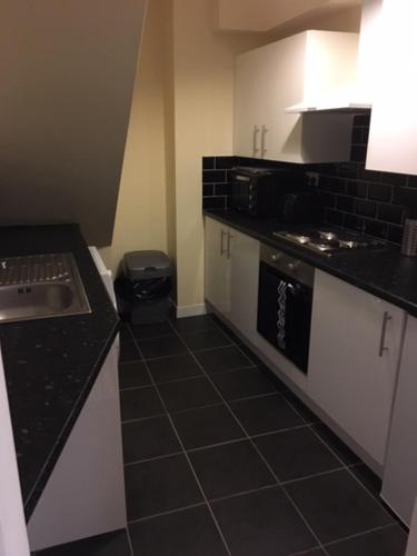 a kitchen with white cabinets and black tile floors at The Winter Garden Suites in Blackpool