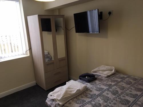 a bedroom with a bed and a television on the wall at The Winter Garden Suites in Blackpool