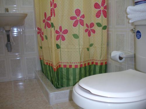 a bathroom with a toilet and a shower curtain with flowers at Hotel Casa Sarita in Bogotá