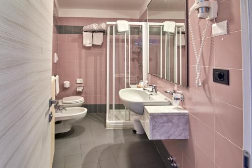 a pink bathroom with a sink and a toilet at Hotel Sole Relax & Panorama in Riva del Garda