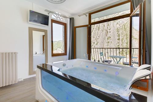 a large bath tub in a room with a window at Hôtel de la Citadelle in Sisteron