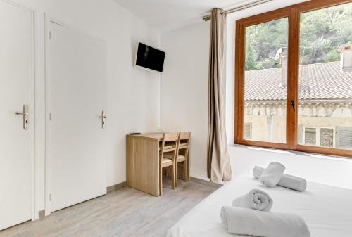 a bedroom with a bed and a desk and a window at Hôtel de la Citadelle in Sisteron