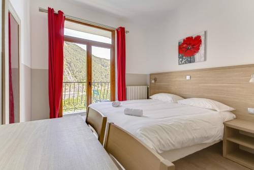 a bedroom with a bed and a large window at Hôtel de la Citadelle in Sisteron