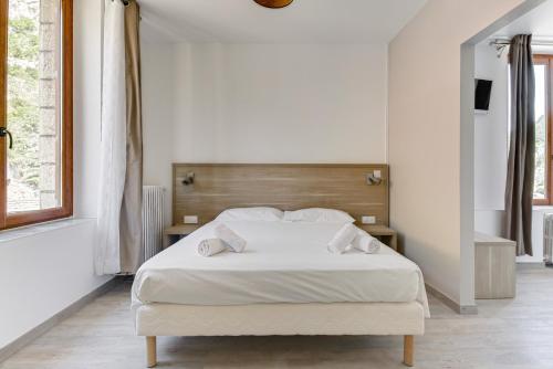 a bedroom with a white bed with a wooden headboard at Hôtel de la Citadelle in Sisteron
