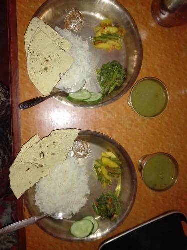 two plates of food with rice and broccoli on a table at kayastha restaurant & lodge in Bandīpur