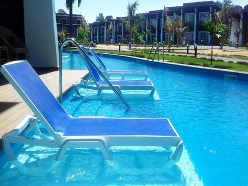two lounge chairs in a swimming pool at African Princess Beach Hotel in Serekunda