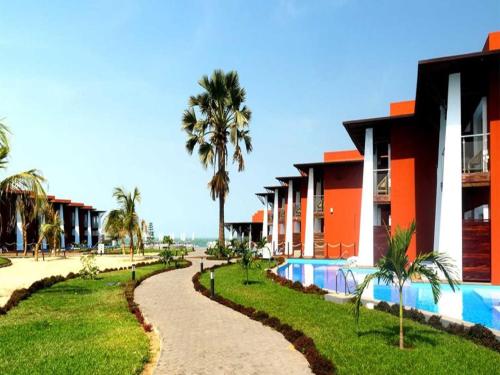 un complejo con piscina y palmeras en African Princess Beach Hotel, en Serekunda