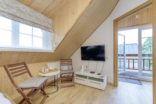 a living room with a table and chairs and a tv at Prie Lukos ezero in Trakai