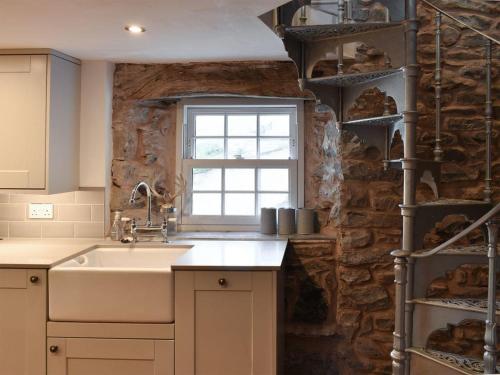 a kitchen with a sink and a stone wall at secret cottage in Sedbergh