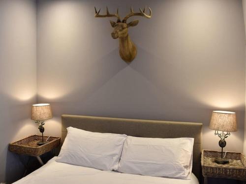 a bedroom with a bed with a deer head on the wall at secret cottage in Sedbergh