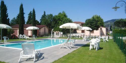 - une piscine avec des chaises et des parasols blancs à côté dans l'établissement Agriturismo Barbarino, à Vinci