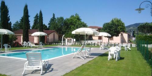 a swimming pool with white chairs and umbrellas next to at Agriturismo Barbarino in Vinci