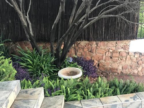 a garden with a stone wall and a bird bath at Bokamoso Views in Rustenburg