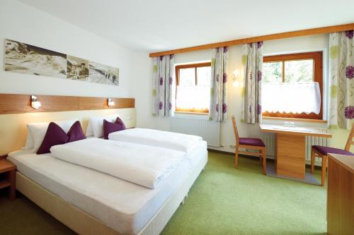 um quarto com uma cama, uma secretária e janelas em Haus Markus Strolz em Sankt Anton am Arlberg