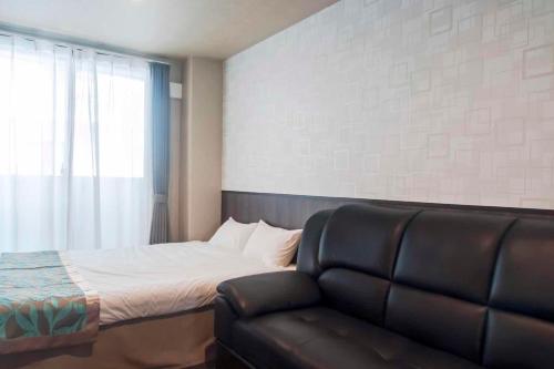 a bedroom with a bed and a leather couch at UU Inn Kyoto in Kyoto