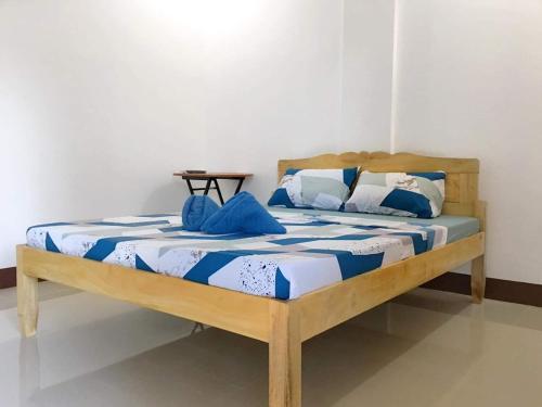 Za Priscila Tourist Inn في أندا: سرير خشبي مع شراشف زرقاء وبيضاء في الغرفة