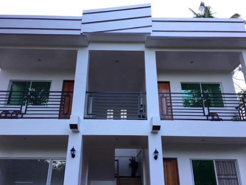 a white building with balconies on the side of it at Za Priscila Tourist Inn in Anda