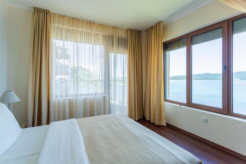 a bedroom with a large bed and large windows at La Casa Primorsko in Primorsko