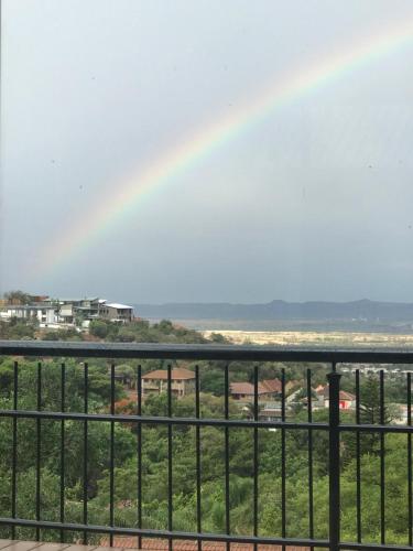a rainbow in the sky over a field with a fence at Bokamoso Views in Rustenburg