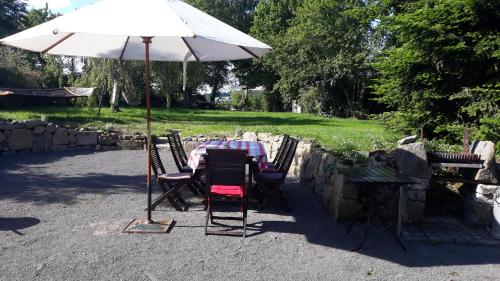 a table and chairs under a white umbrella at La Grange in Rânes