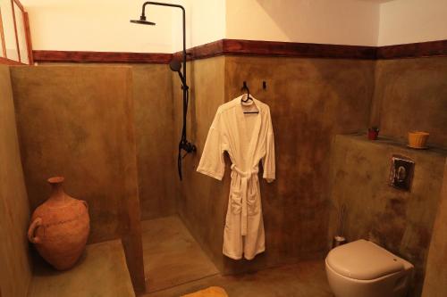 a bathroom with a white robe and a toilet at Casa Colonial Koenig in São Filipe