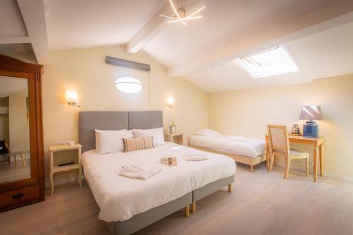 a bedroom with a large bed and a desk with a chair at Hotel les Armoiries in Valbonne