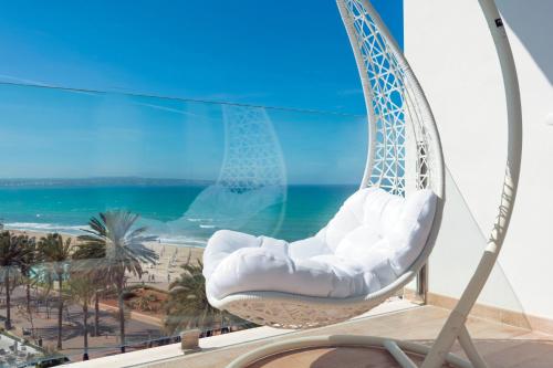 a swinging chair on a balcony with a view of the beach at HSM Golden Playa in Playa de Palma