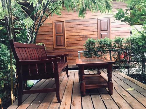 a bench and a table and a chair on a deck at 88 Homestay in Bang Chak