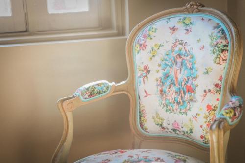 a floral chair in a corner of a room at Le manoir des chevaux dorés in Le Neubourg