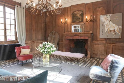 a living room with a fireplace and a table and chairs at Le manoir des chevaux dorés in Le Neubourg