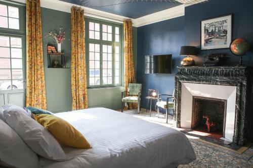 a blue bedroom with a bed and a fireplace at Le manoir des chevaux dorés in Le Neubourg